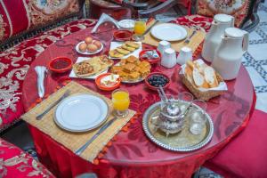a red table with breakfast foods and orange juice at Riad Fes iline Medina in Fez