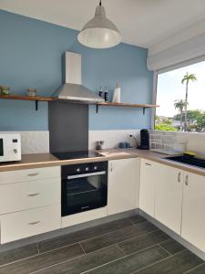 a kitchen with white cabinets and a large window at L'Echappée Créole - Vue mer Terminal Ferry - Pointe-à-Pitre in Pointe-à-Pitre