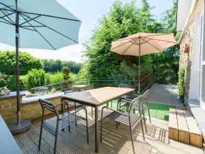 a patio with a table and chairs and an umbrella at Moderscheid Cottage with Spa in Amblève