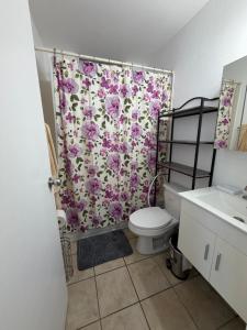 a bathroom with a toilet and a floral shower curtain at josedith'sweet house in Isabela