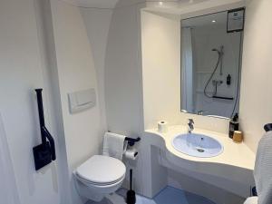 a white bathroom with a toilet and a sink at Ibis Budget Ancenis in Mésanger +62 photos