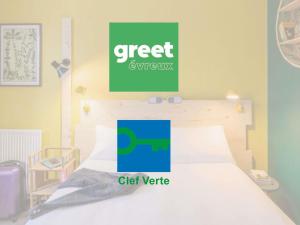 a bedroom with a bed with a green sign on the wall at Greet Hotel Evreux Centre - Route de Normandie by Accor in Évreux