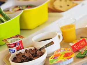a tray with a bowl of food and a cup of coffee at ibis budget Amberieu en Bugey/Chateau Gaillard A42 in Château-Gaillard