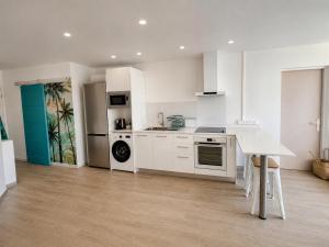 a kitchen with white cabinets and a table in it at Centre Ville Fare Vairahi in Uturoa