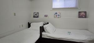 two beds in a bedroom with white sheets and pillows at Bright 2 BR, Great Location in West Vancouver