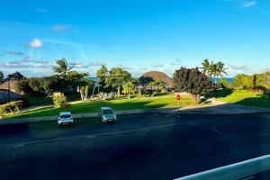 two cars parked in a parking lot next to a golf course at Centre Ville Fare Vairahi in Uturoa