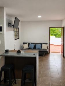 a living room with a couch and a kitchen with stools at Hotel Sun River in Barranquilla