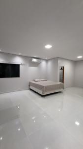 a white bedroom with a bed and a flat screen tv at Casa moderna próximo ao bumbodromo in Parintins