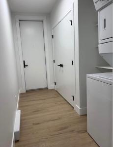 a kitchen with two white doors and a wooden floor at Upscale One Bedroom Suite in New Build in Kelowna