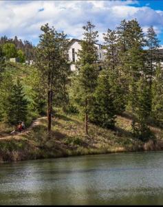 a house on top of a hill next to a river at Upscale One Bedroom Suite in New Build in Kelowna