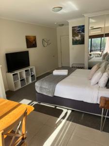 a bedroom with a bed and a flat screen tv at Beach Studio with Ocean View in Gnarabup +13 photos