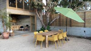 a wooden table with yellow chairs and an umbrella at CASA NU La Saladita surf point in Temalhuacán
