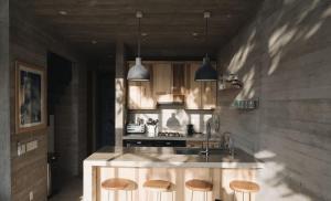 a kitchen with a island with wooden stools at CASA NU La Saladita surf point in Temalhuacán
