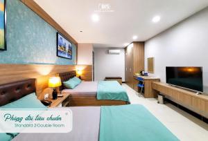 a hotel room with two beds and a flat screen tv at Bis Hotel Hồ Chí Minh in Chợ Phước Hải