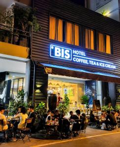 a group of people sitting at tables in front of a restaurant at Bis Hotel Hồ Chí Minh in Chợ Phước Hải