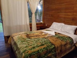 a bed in a room with a tiger blanket on it at Rancho San Andrés in Palora