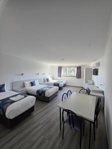 a hotel room with two beds and a table at Hume Villa Motor Inn UNDER NEW MANAGEMENT in Melbourne