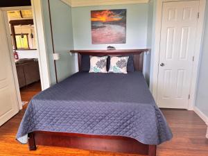 a bedroom with a bed with a purple comforter at Pau Hana Paradise in Hana