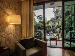 a living room with a chair and a view of a pool at Mercure Iguazu Hotel Iru in Puerto Iguazú +112 photos