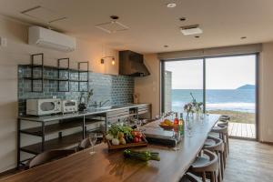 a kitchen with a long table with a view of the ocean at THE SHIKAKA Hotel&Resort BUDOUNOKI in Itoshima