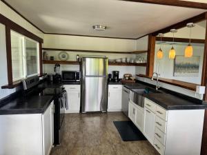 a kitchen with white cabinets and a stainless steel refrigerator at Pau Hana Paradise in Hana
