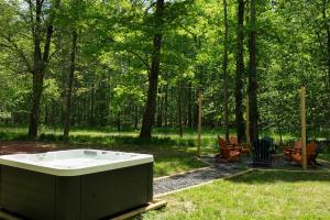 a bath tub sitting in the grass in a park at Tucked in the Woods - Jacuzzi Firepit Pooltable in Long Pond