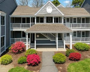 a house with a porch and flowers in front of it at New Cape Cod Condo Near Beaches in Brewster