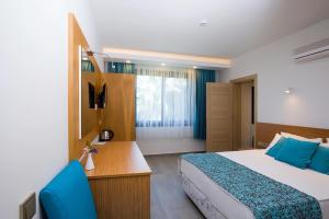 a hotel room with a bed and a desk and a television at My Marin Otel in Turgutreis