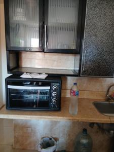 a microwave and a bottle of water on a kitchen counter at لاسرينا عيون موسي in Az Zaytīyah +2 photos