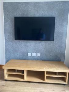a television on a wall with a wooden table at Pure Home Oakley Central TBA in Dunfermline