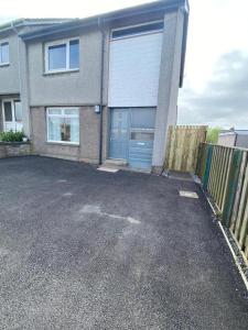 a house with a blue garage door in a parking lot at Pure Home Oakley Central TBA in Dunfermline