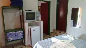 um quarto com uma cama e uma televisão e um suporte de televisão em Pousada Recanto do Sossego em São Tomé das Letras