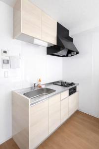 a white kitchen with a sink and a stove at Arch Garden in Ishihara