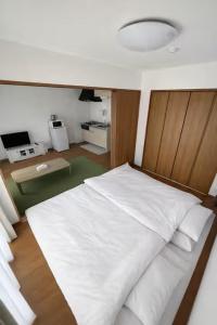 a bedroom with a white bed with a wooden headboard at Arch Garden in Ishihara