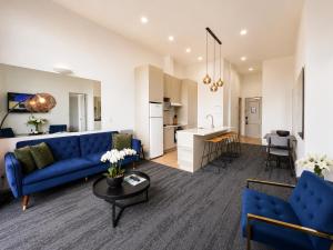 a living room with a blue couch and a kitchen at Quest on Eden Auckland CBD Apartment Hotel in Auckland