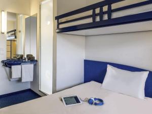 a bedroom with a bed with a laptop and headphones at ibis budget Libourne in Libourne +25 photos