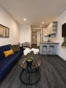 a living room with a blue couch and a table at Quest on Eden Auckland CBD Apartment Hotel in Auckland