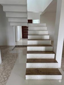 a staircase in a house with white walls and wooden floors at Quarto Suíte Master Luxo in Santana do Livramento