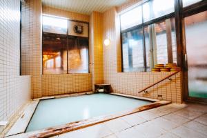 a bathroom with a tub in a room with windows at ZAO SPA HOTEL Kiraku in Zaō Onsen