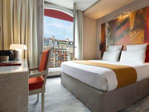 a hotel room with a bed and a large window at Mercure Paris Alesia in Paris