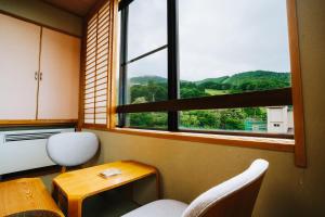a room with a table and two chairs and a window at ZAO SPA HOTEL Kiraku in Zaō Onsen