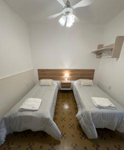 two beds in a room with a ceiling fan at Lo de Mingo in San Pedro