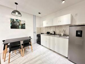 a kitchen with white cabinets and a table in it at Vela Villa Apart N3 in Villa Ángela