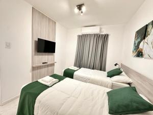a bedroom with two beds and a flat screen tv at Vela Villa Apart N3 in Villa Ángela