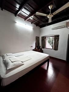 a bedroom with a large bed and a ceiling fan at Remasailam Homestay - Thiruvananthapuram , Calm & Blend with Nature in Trivandrum