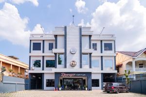 a white building with a car parked in front of it at SANS Hotel Bobo Home Jambi in Jambi