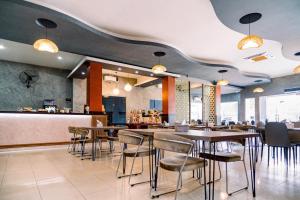 a restaurant with tables and chairs and a bar at SANS Hotel Bobo Home Jambi in Jambi