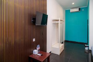 a room with a tv on a wall with a table at SANS Hotel Bobo Home Jambi in Jambi