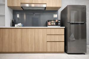 a kitchen with a stainless steel refrigerator and wooden cabinets at Luxumiere Apartment with Resort Pool - Elite Gym in Ho Chi Minh City