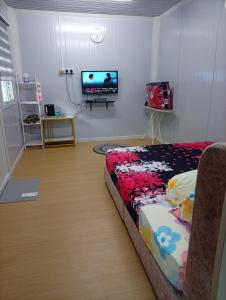 a room with a bed and a flat screen tv at D'Cabin Roomstay in Sungkai